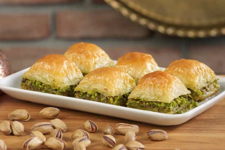 A tray of diamond-cut baklava with honey syrup and chopped walnuts