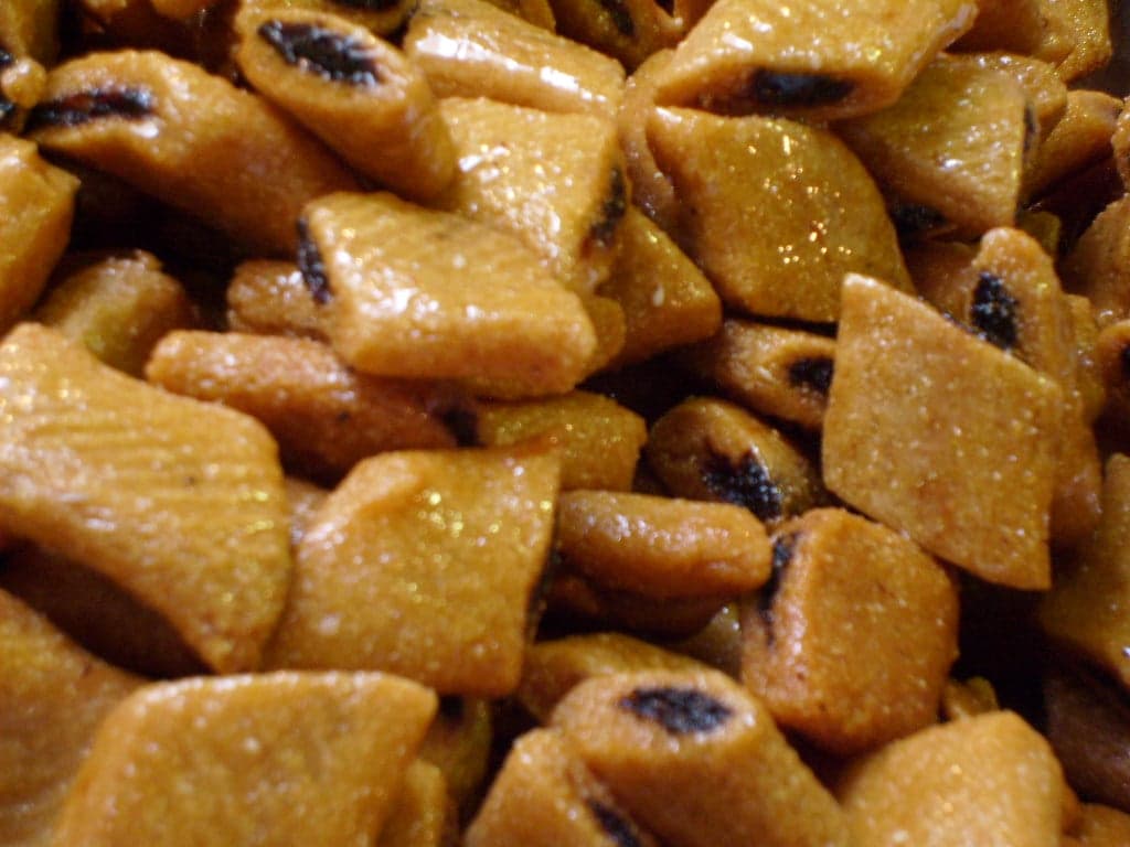 A tray of golden diamond-shaped makroud pastries glistening with honey