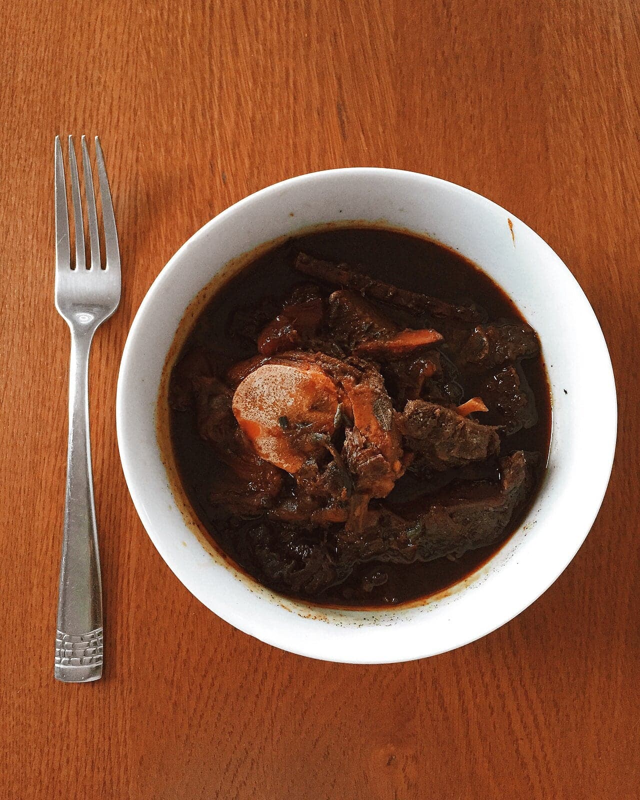 A bowl of fungee and pepperpot stew on a table