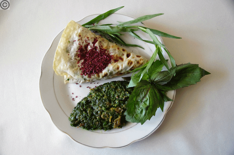 A stack of golden half-moon qutab flatbreads dusted with herbs