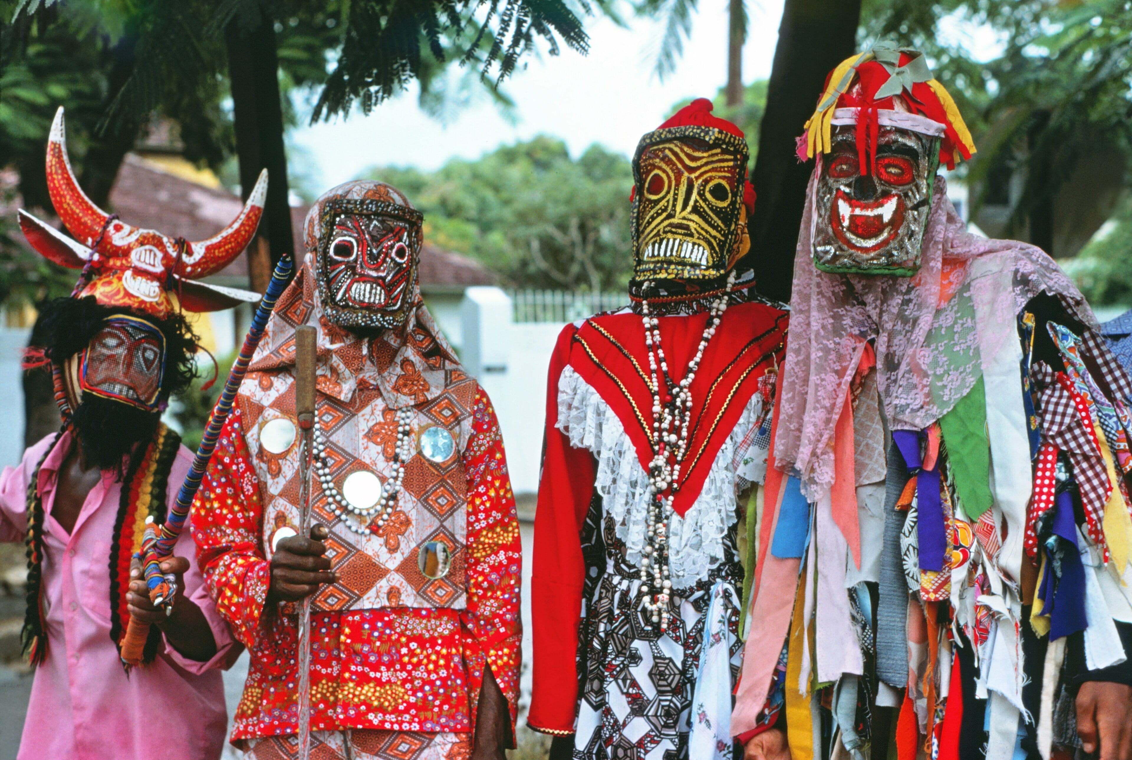 Junkanoo musicians in bright costumes playing drums and cowbells at night