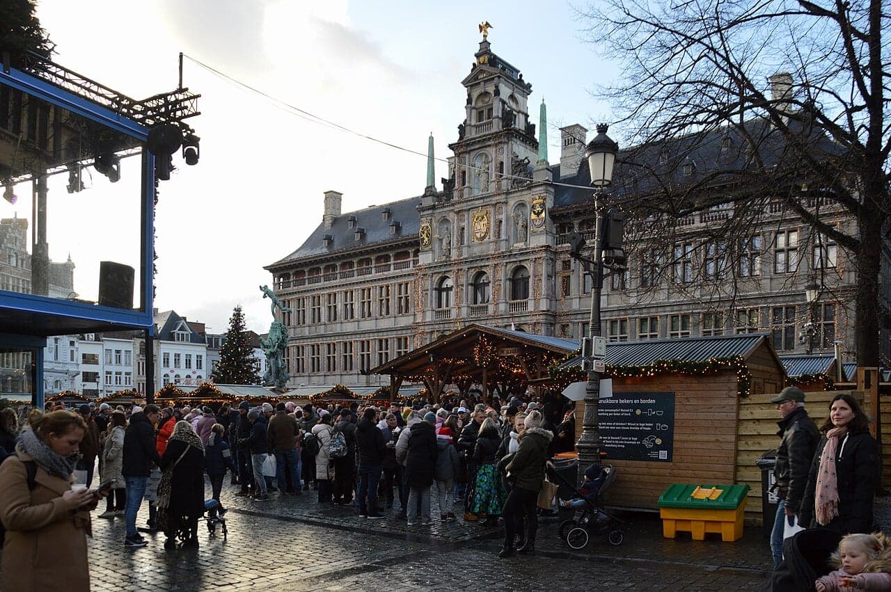 A glowing Christmas market in a large square in Brussels with a tall decorated tree