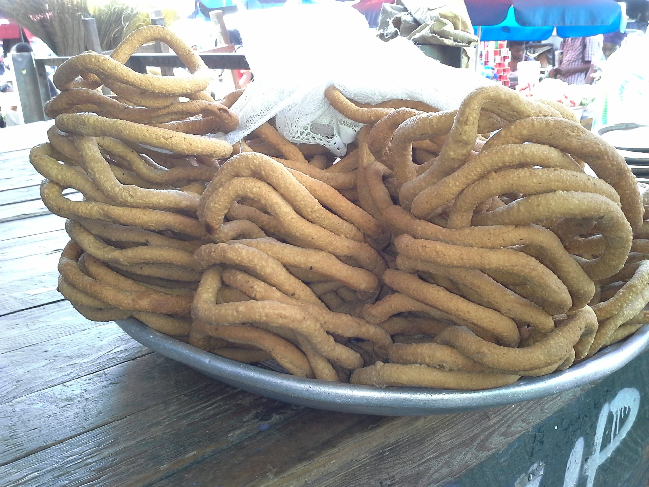 Golden-brown kuli-kuli peanut snacks in different shapes arranged on a colourful cloth