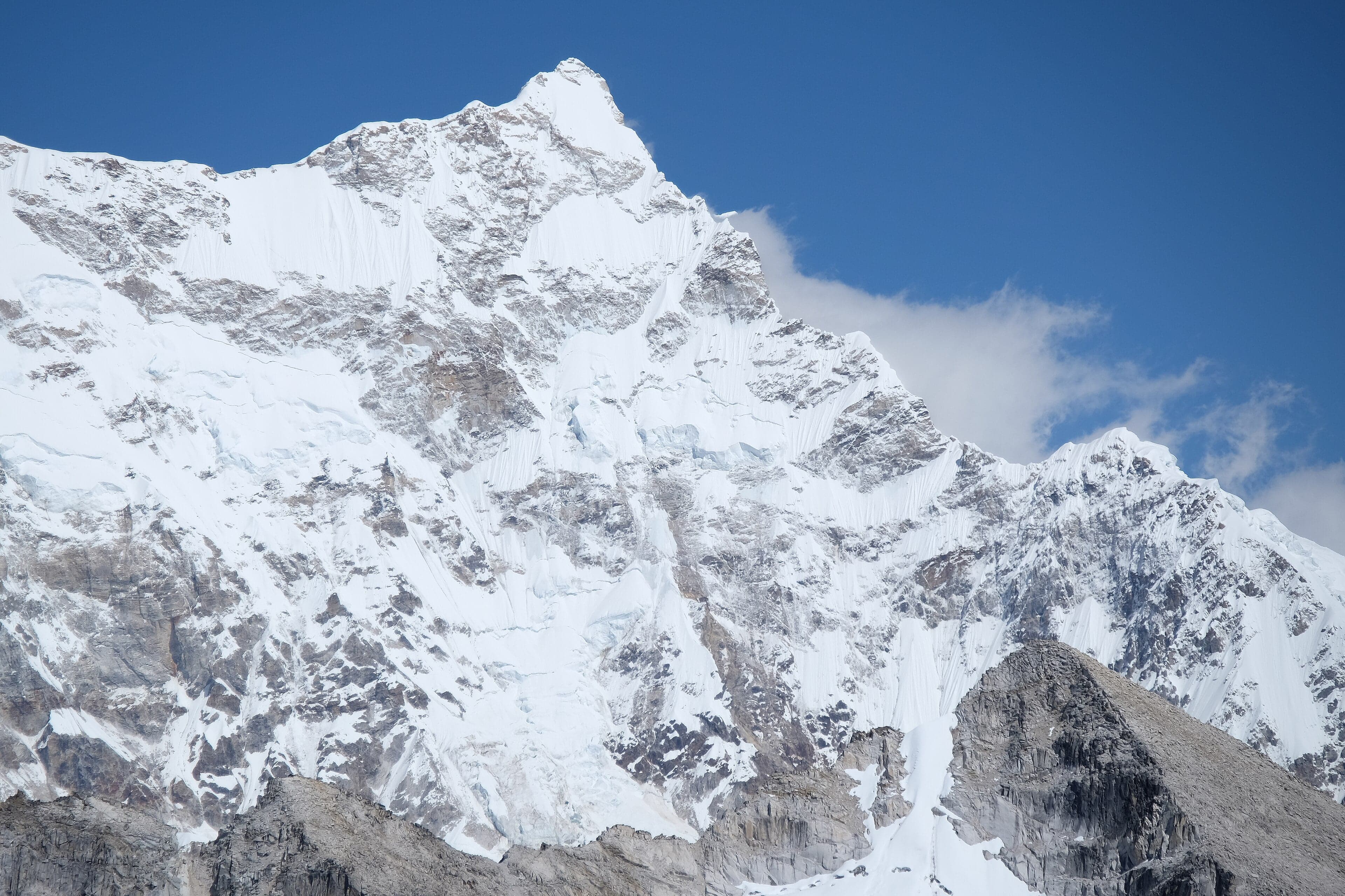 Snow-covered Gangkhar Puensum mountain peak rising above clouds in Bhutan