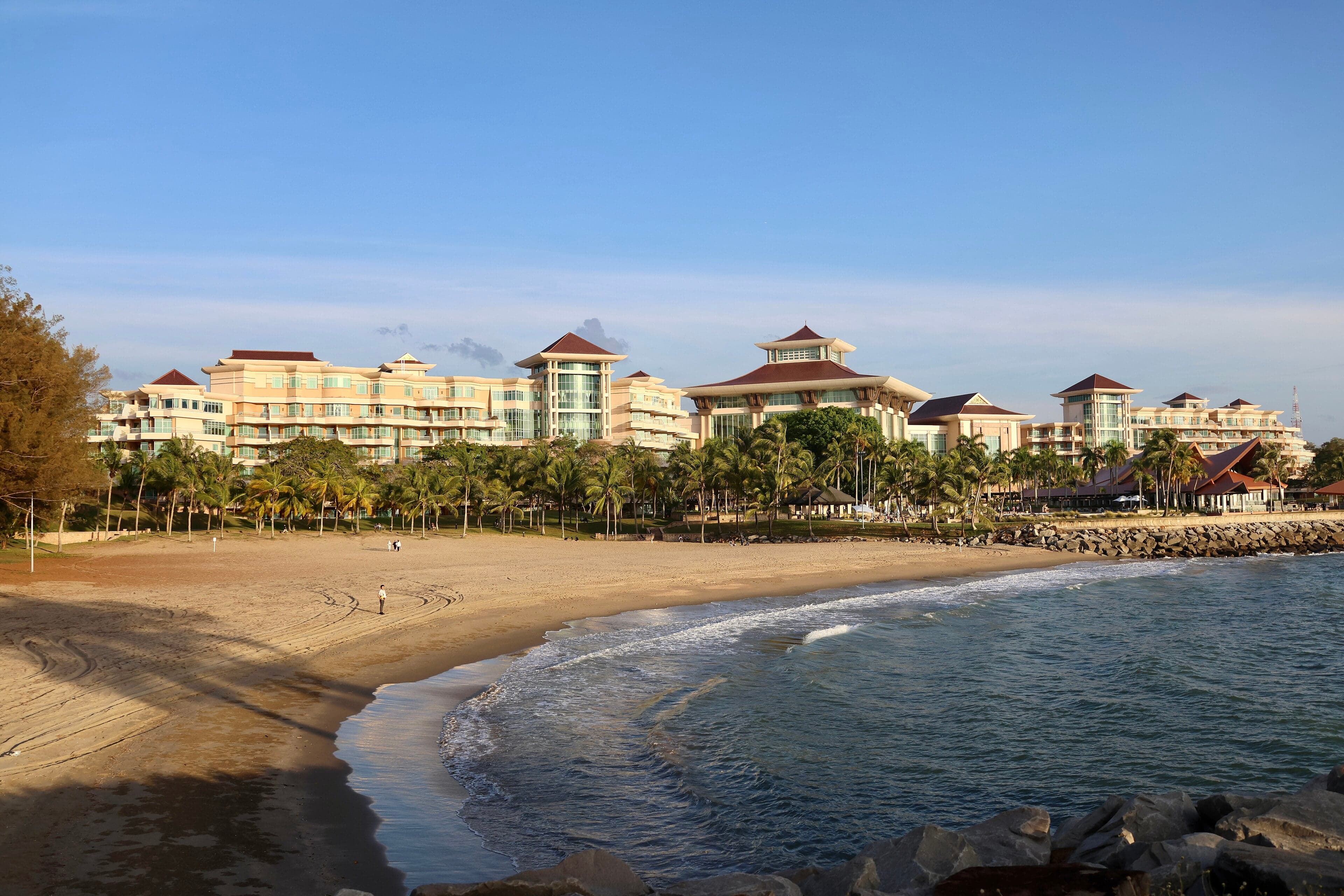The golden exterior of the Empire Hotel surrounded by tropical gardens and the sea
