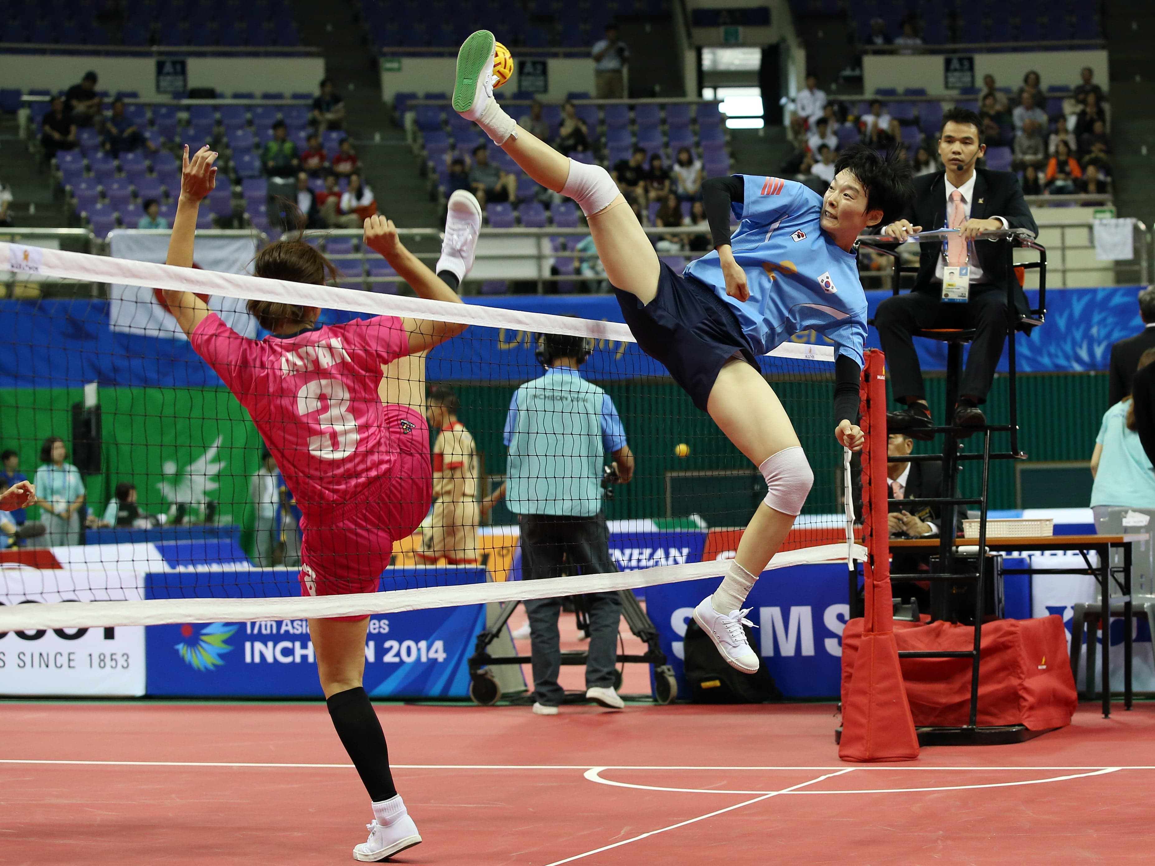 A player performing a spectacular bicycle kick to hit a rattan ball over the net in sepak takraw