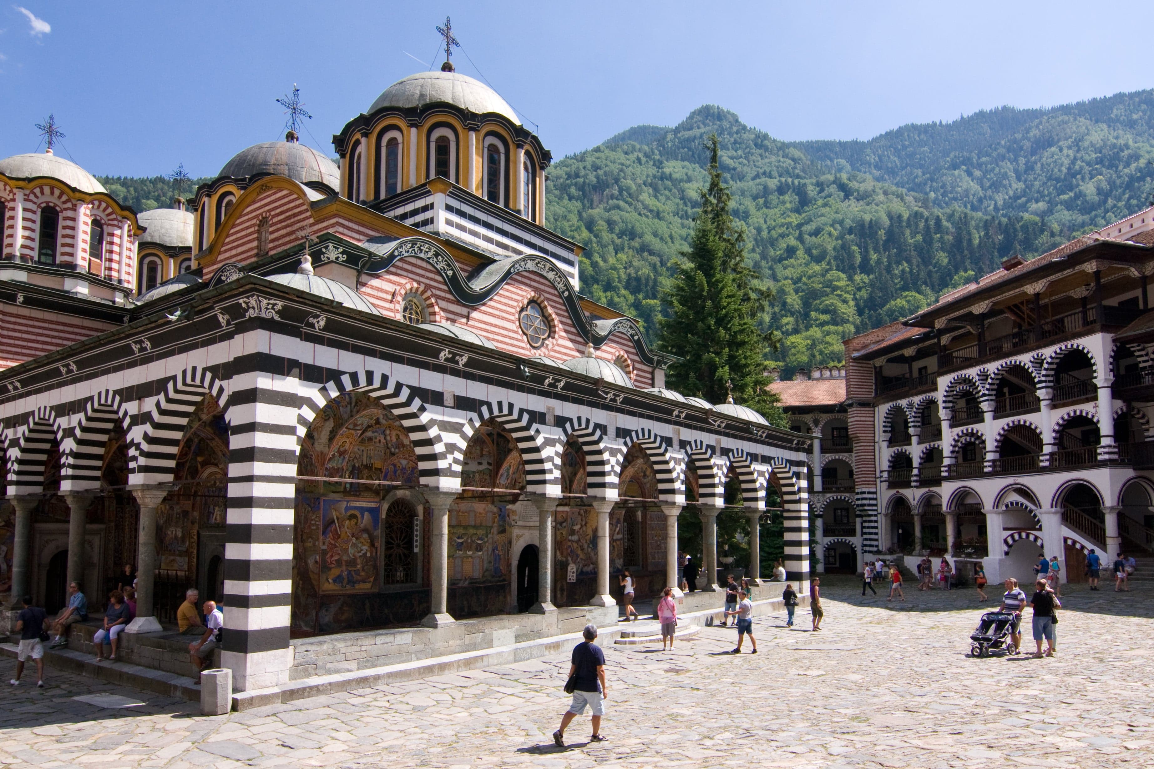 The colourful arched courtyards of Rila Monastery surrounded by pine-forested mountains