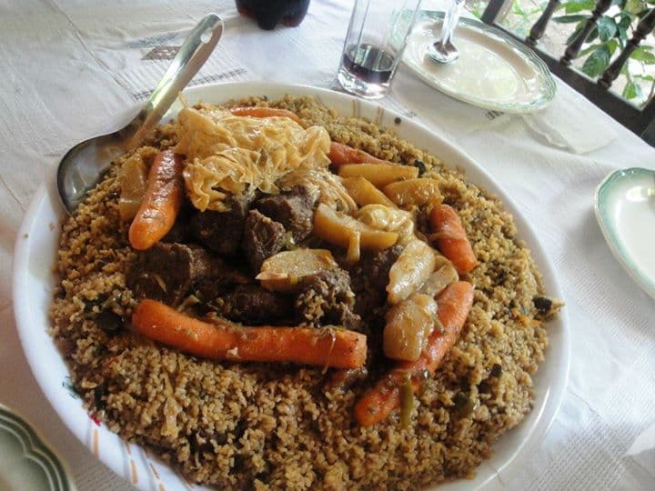 A large bowl of riz gras with colourful vegetables cooked into the orange-tinted rice