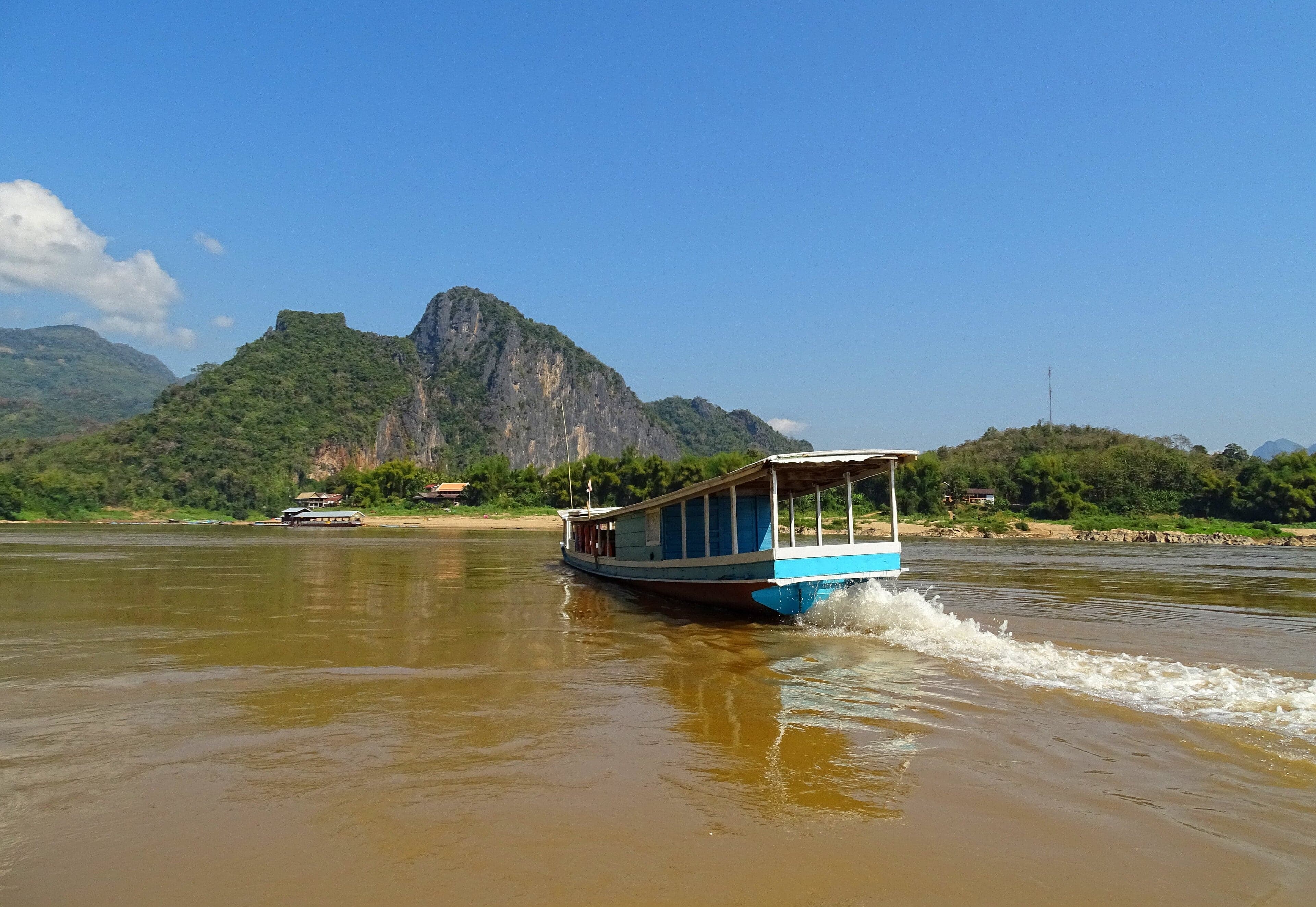 The wide brown Mekong River at sunset with fishing boats
