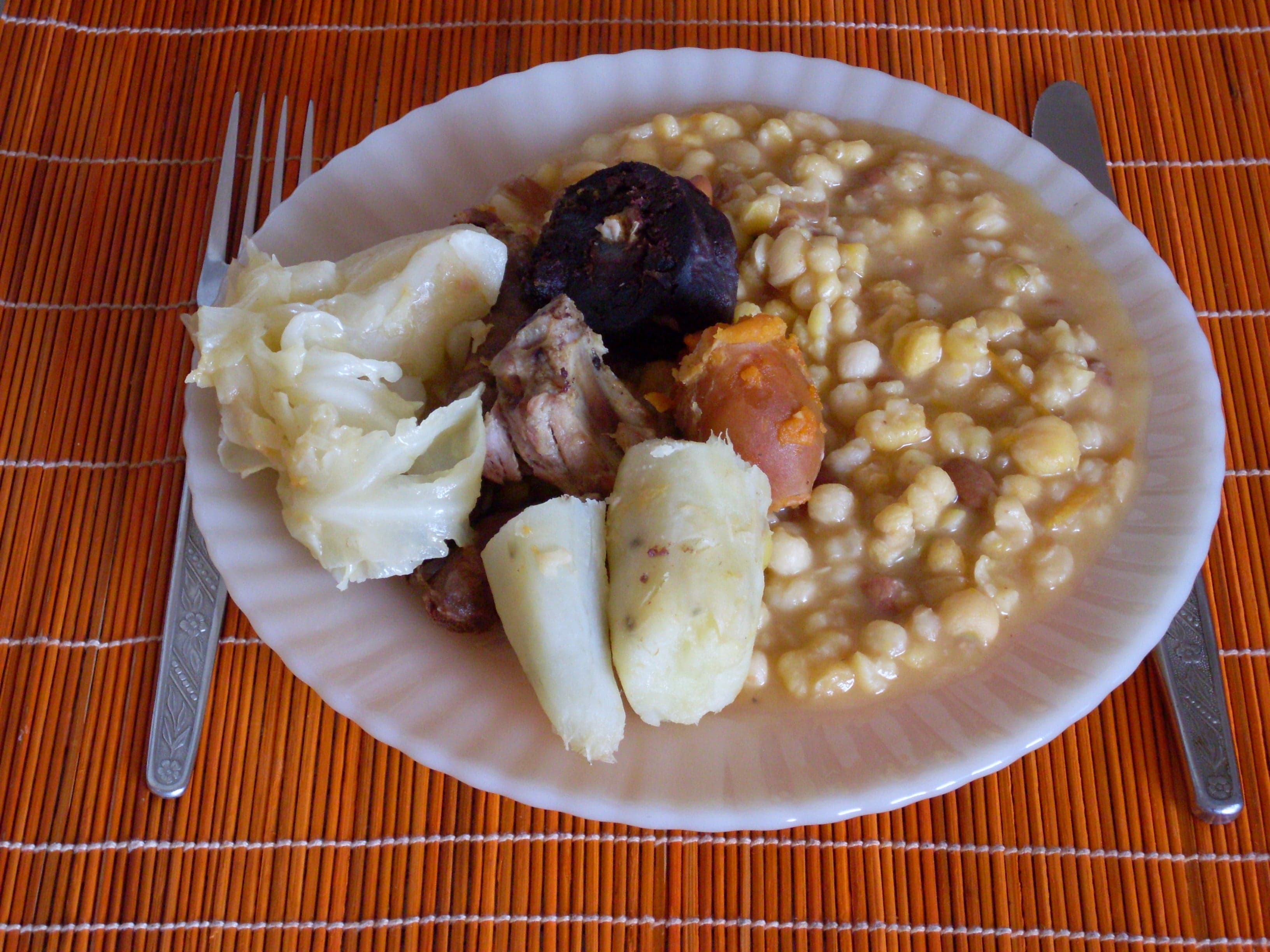 A large clay pot of cachupa stew with maize, beans and vegetables, steam rising