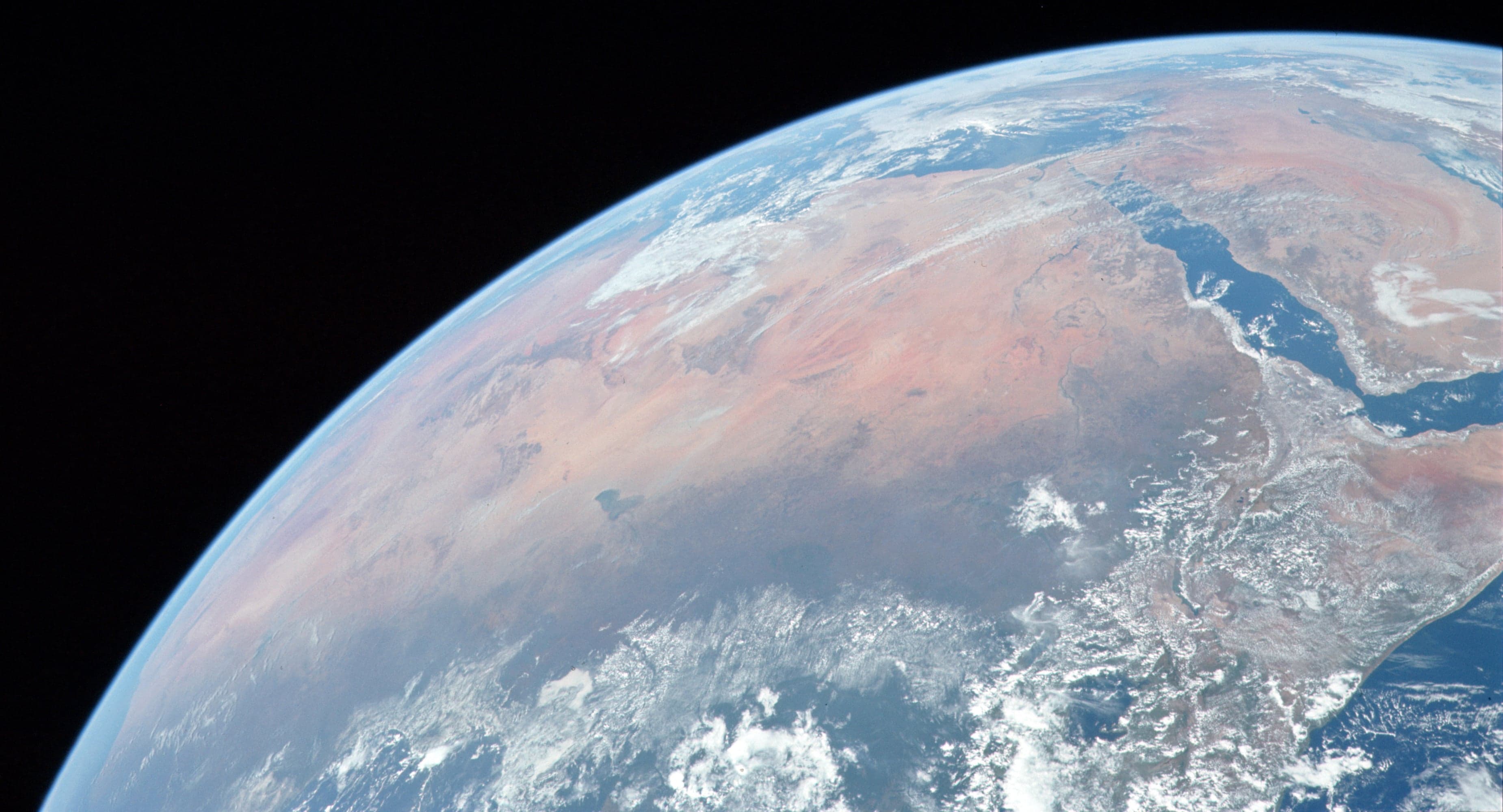 Vast orange sand dunes of the Sahara under a deep blue sky