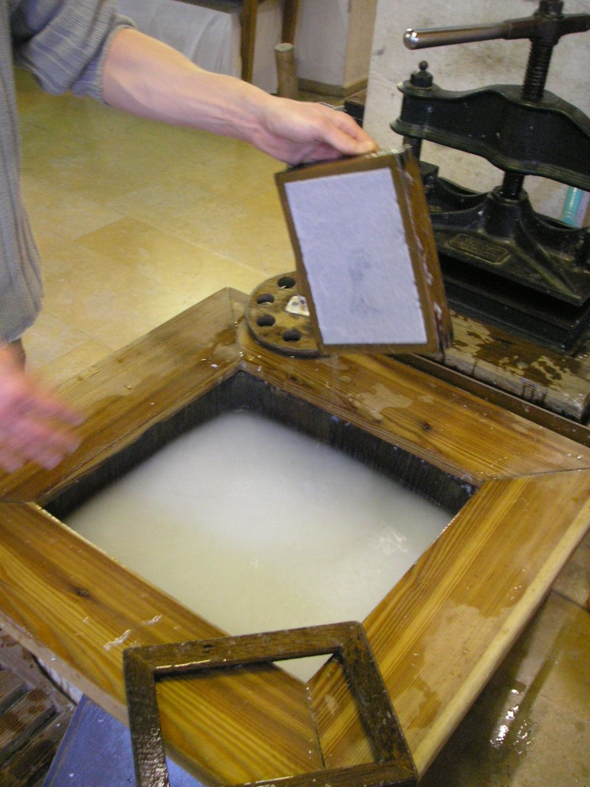 A traditional papermaker pressing a fresh sheet of handmade paper
