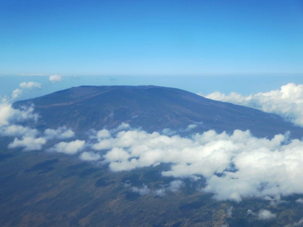 The green slopes of Mount Karthala volcano rising above the clouds on Grande Comore