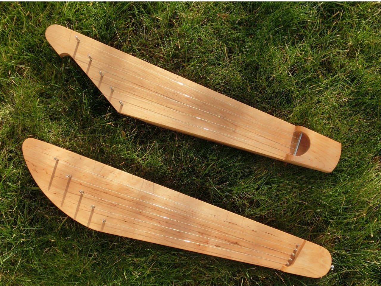 Two traditional five-string Finnish kanteles laid on grass, showing their boat-like wooden bodies