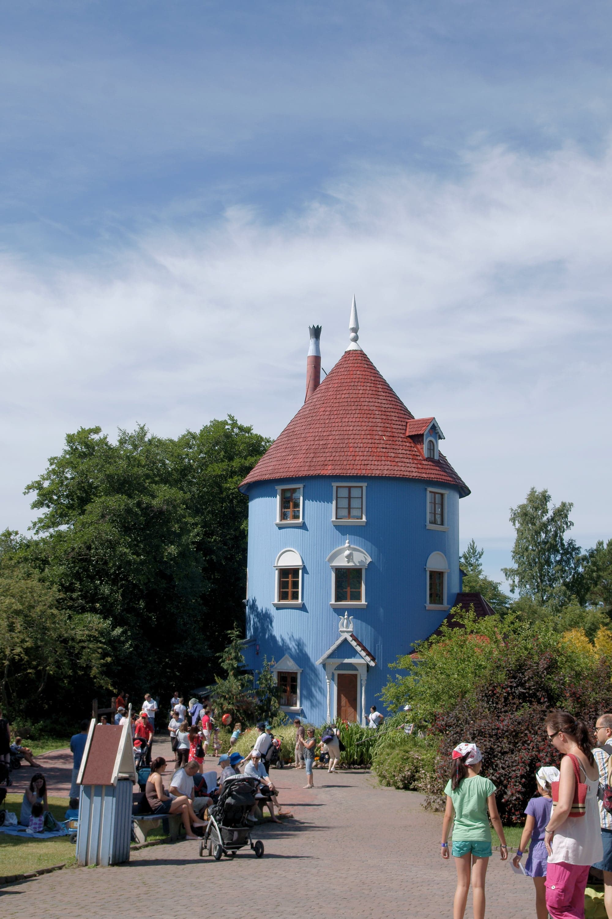 The tall, round blue Moomin house at Moomin World theme park in Naantali, with families visiting on a sunny day