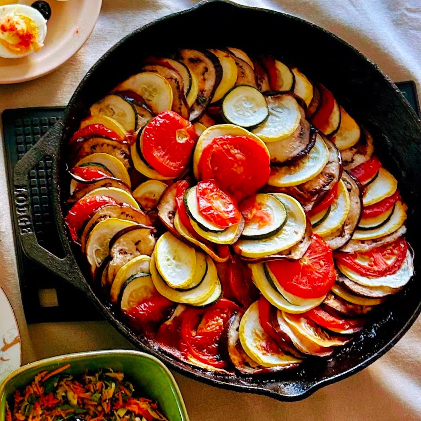 A round dish of ratatouille with sliced vegetables arranged in a pattern