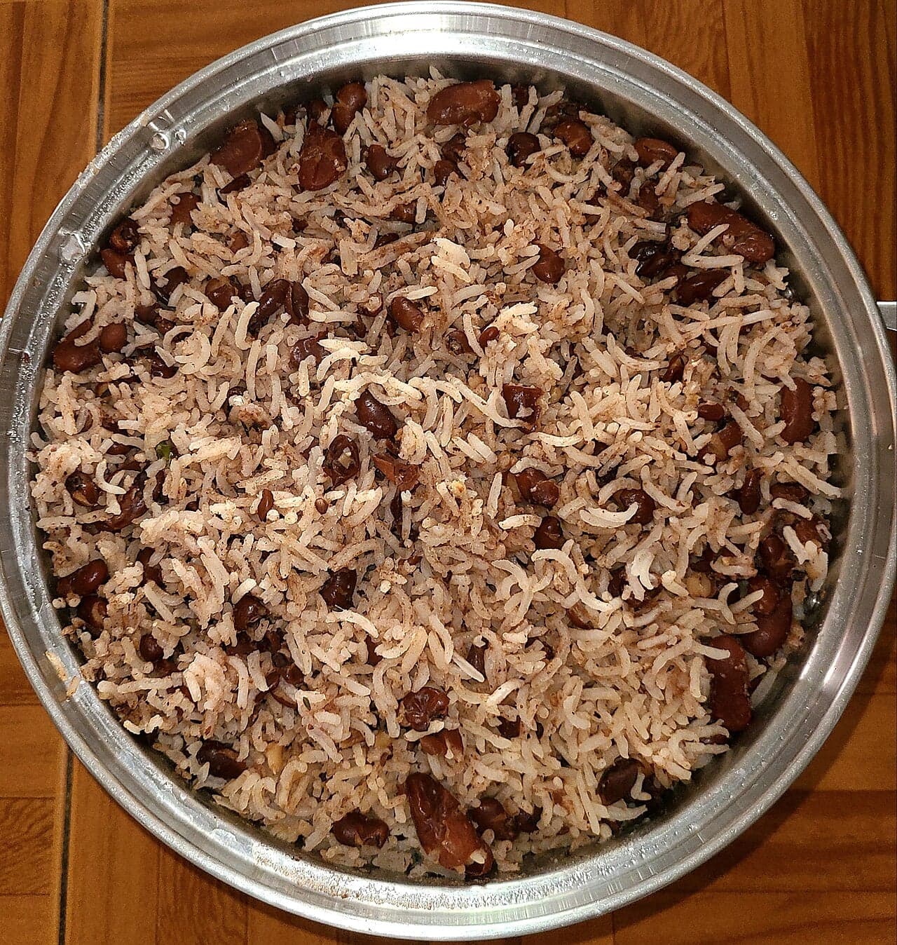 A bowl of Guyanese cookup rice with black-eyed peas and coconut, garnished with herbs