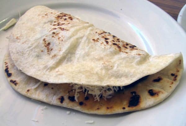 A freshly made Honduran baleada - a folded flour tortilla filled with refried beans, cream, and cheese