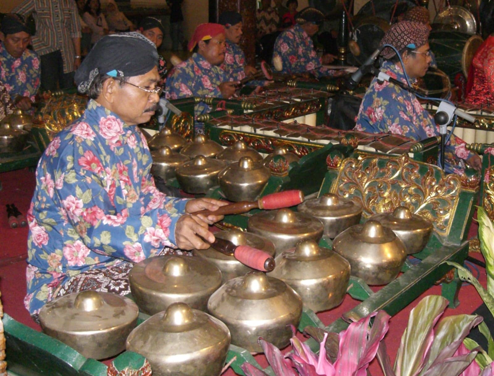 Musicians playing rows of bronze gongs and metal instruments in a gamelan orchestra
