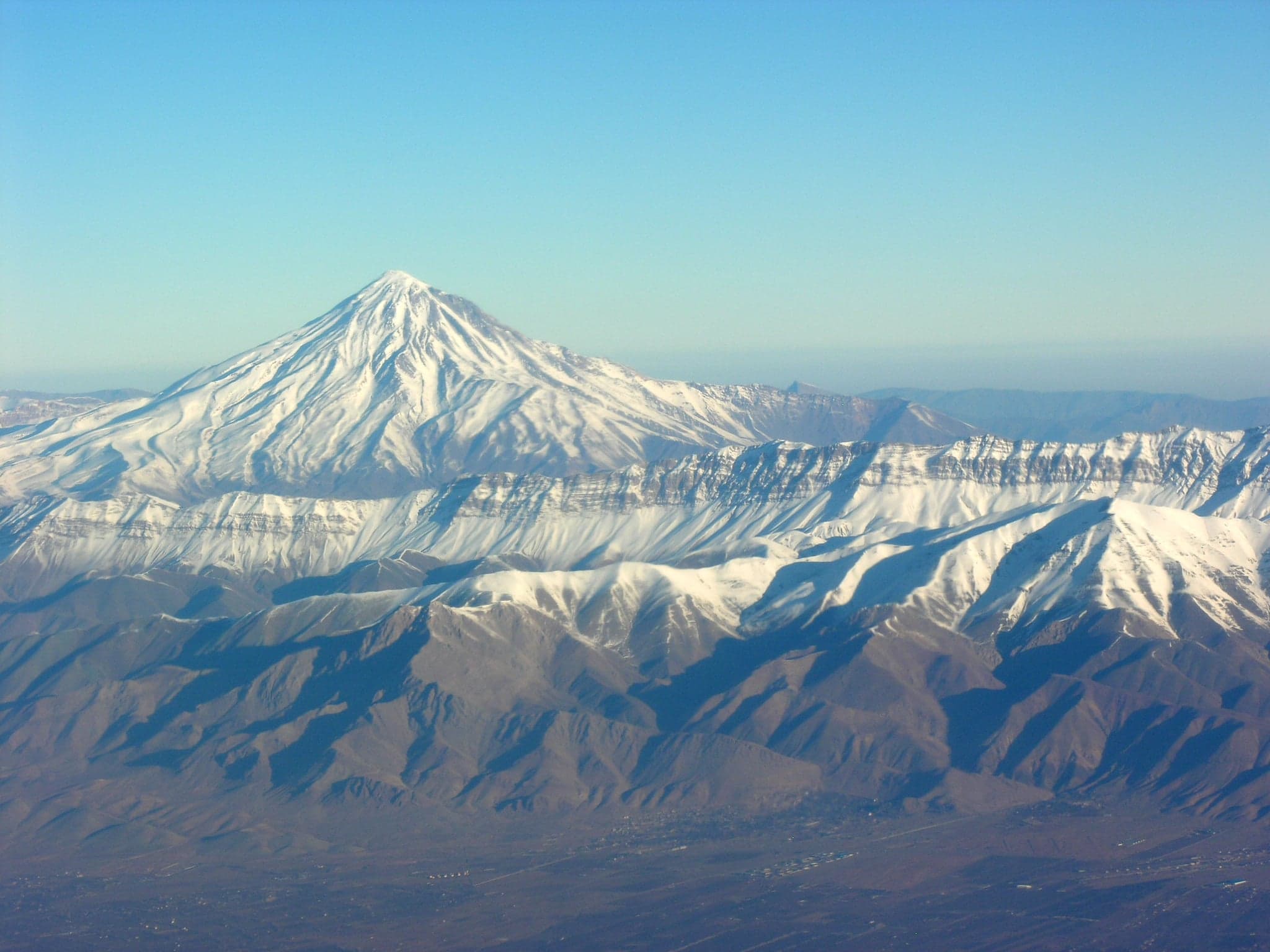 Snowy peaks of the Alborz Mountains above green valleys with a blue sky