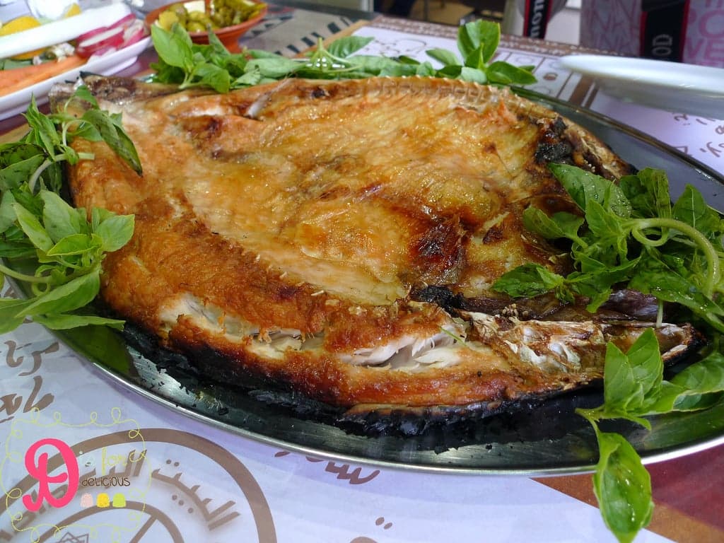 A large fish opened flat and grilled over an open wood fire on the banks of the Tigris