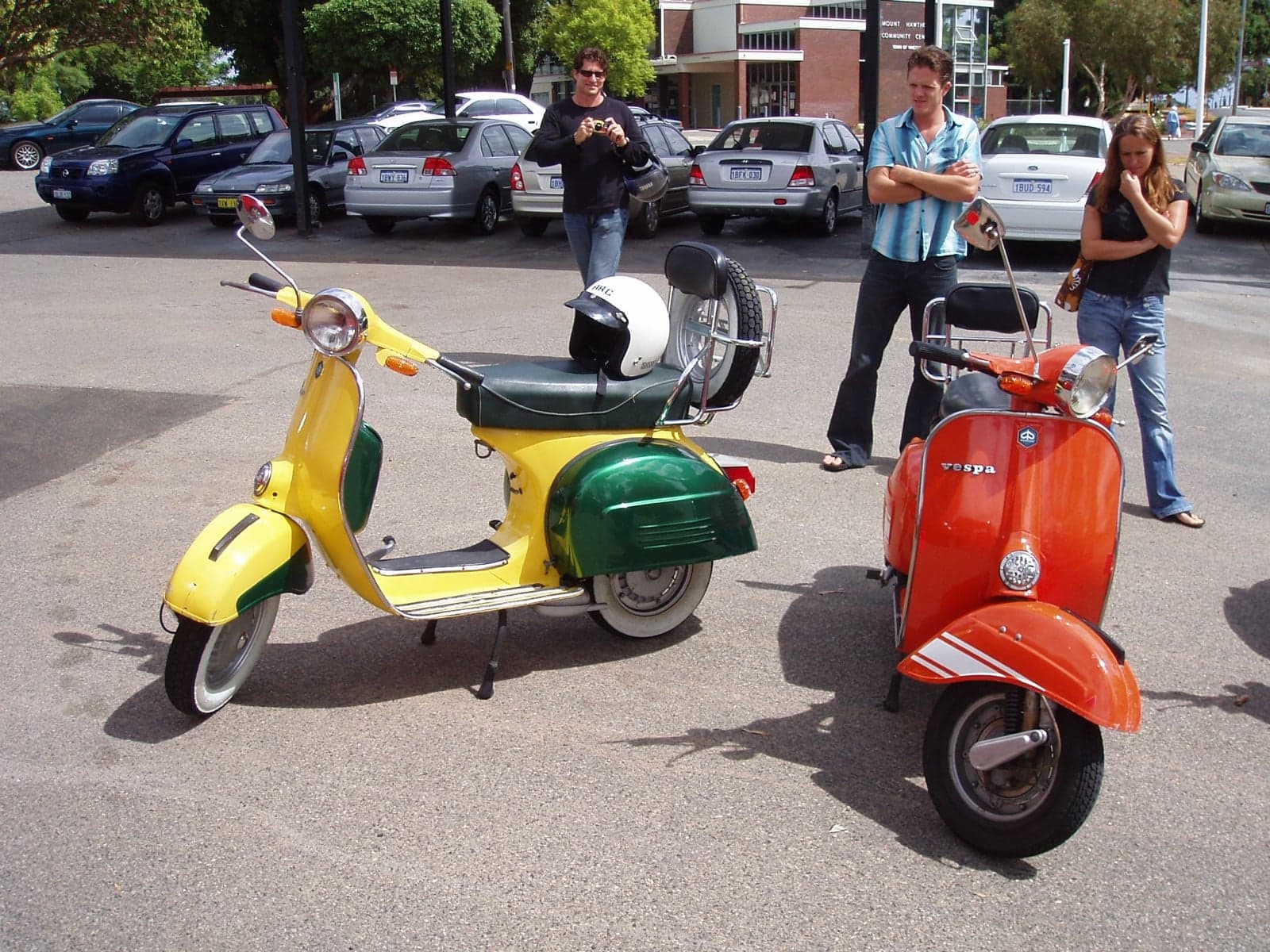 A yellow Vespa and a red Vespa parked next to each other