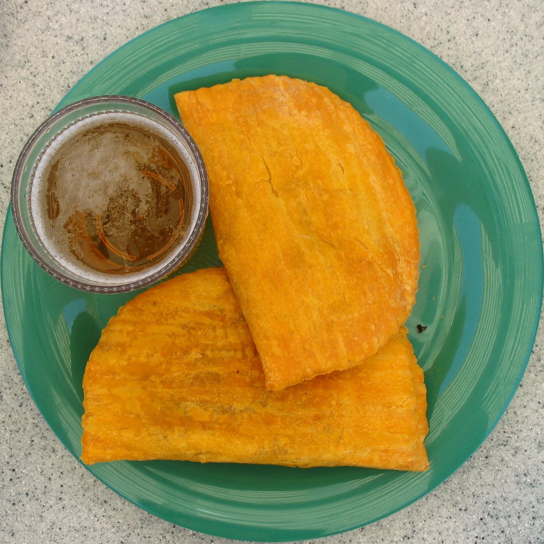 Two bright yellow Jamaican beef patties on a white paper wrapper