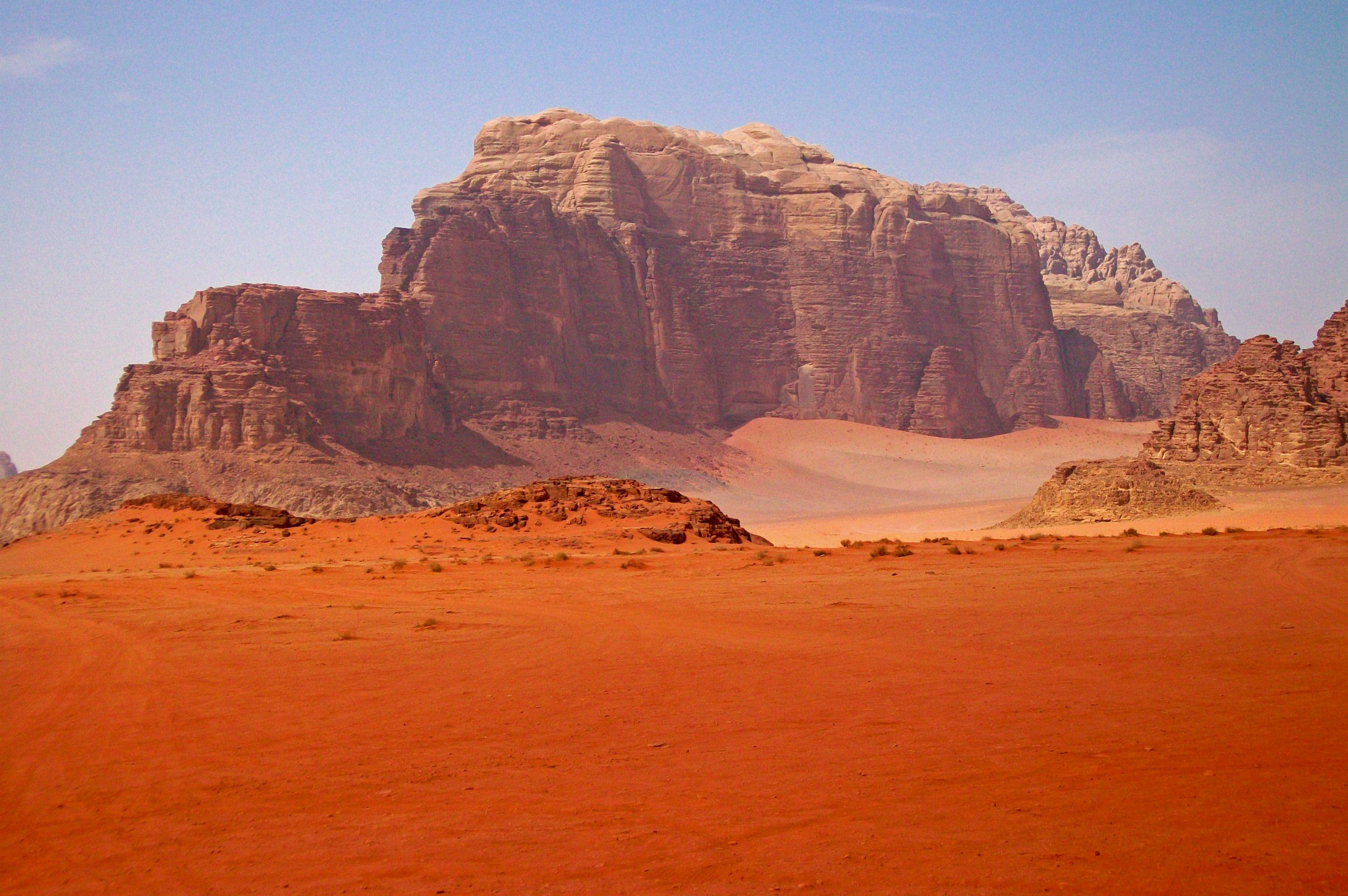 Towering red sandstone pillars rising from the golden desert of Wadi Rum at sunset