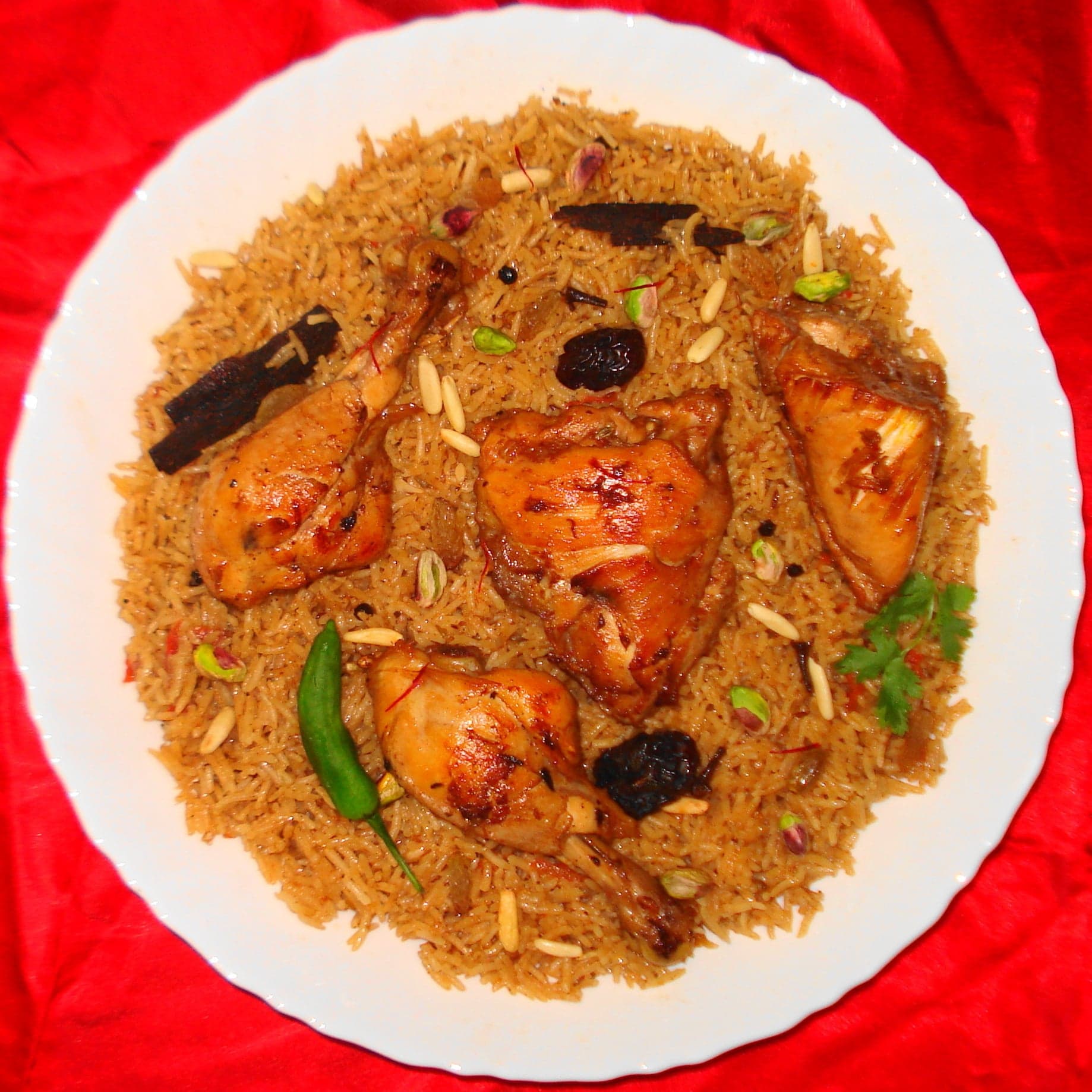 A large serving dish of machboos - golden spiced rice topped with chicken and fried onions