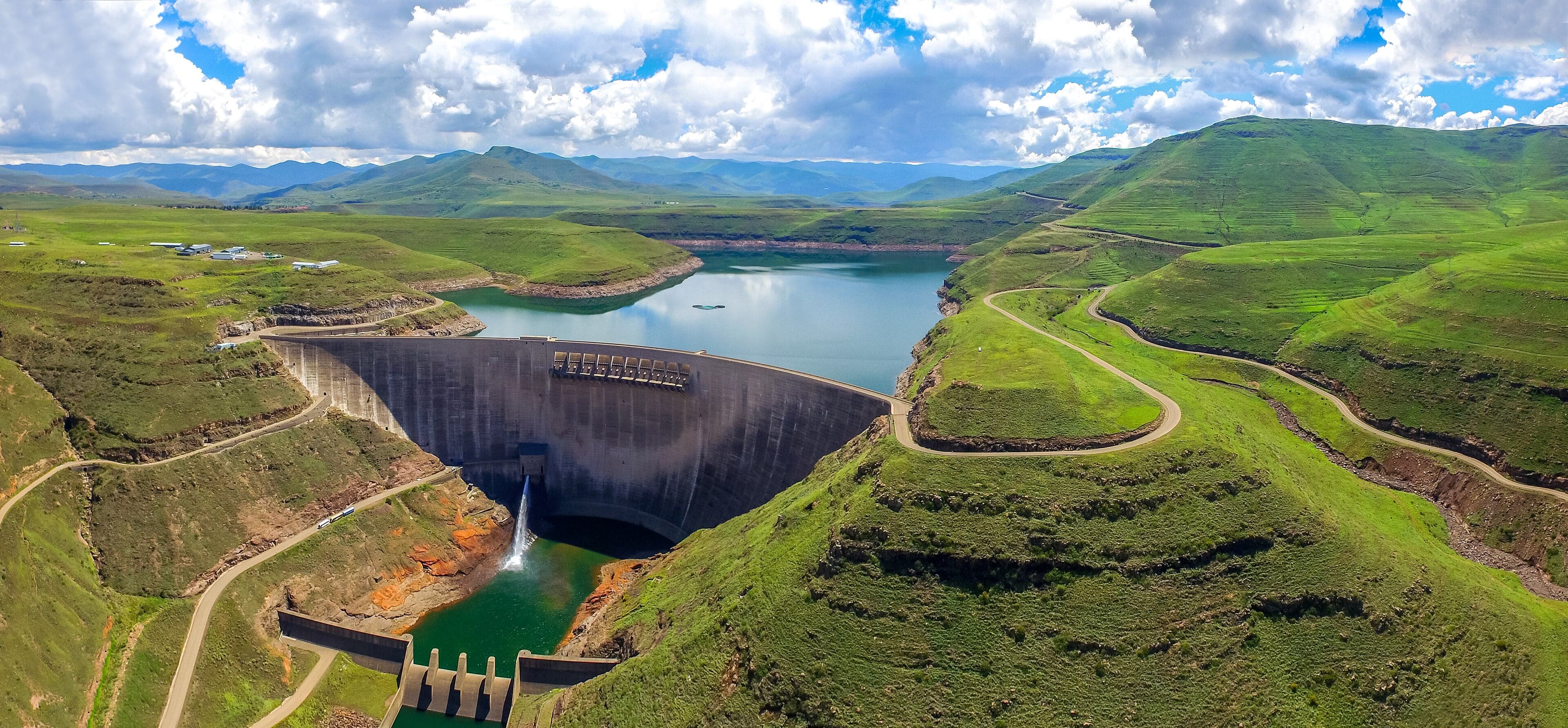 The curved white wall of Katse Dam holding back a deep blue reservoir in the mountains