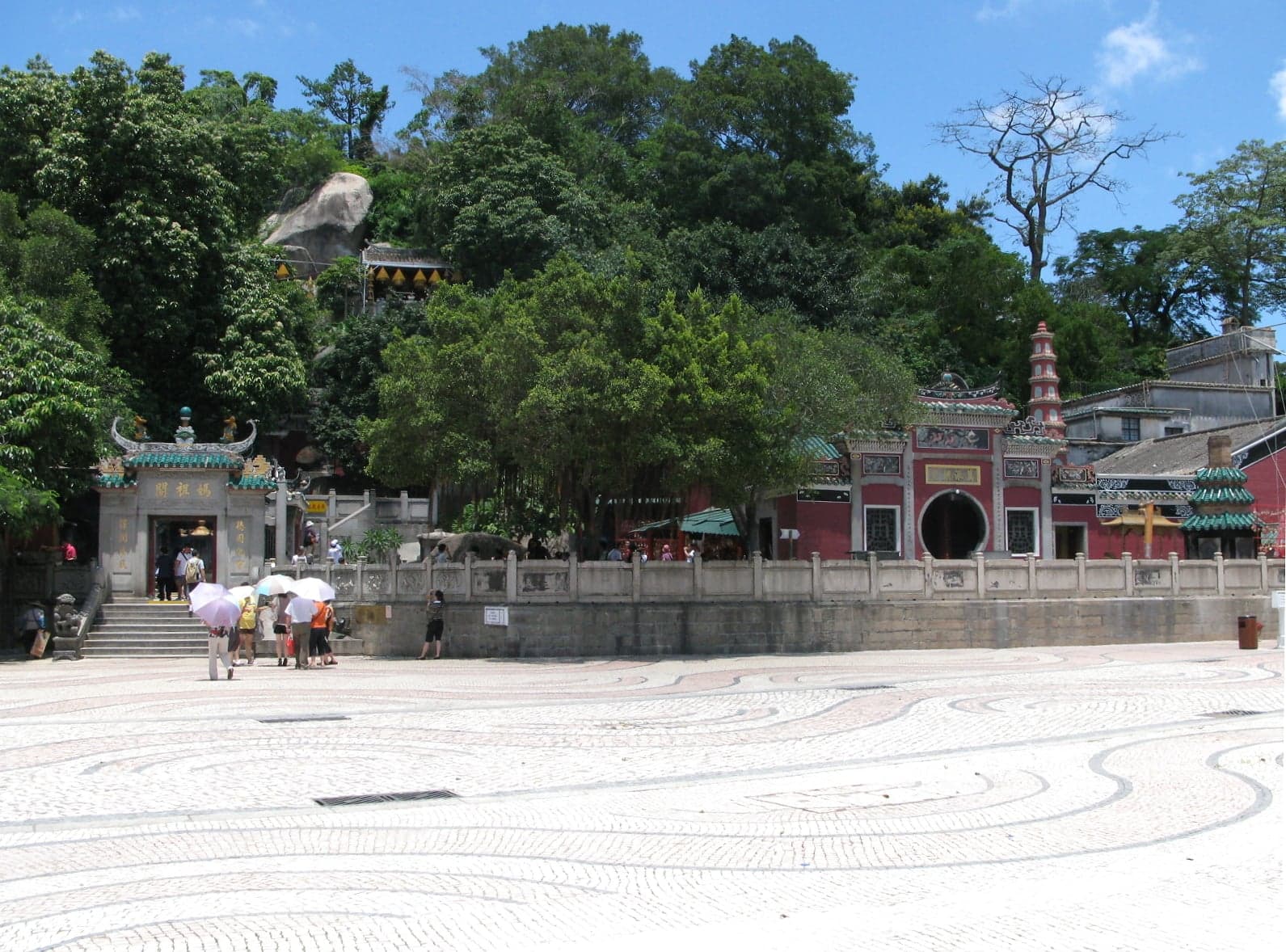 The red gates and curved rooftops of A-Ma Temple in Macau surrounded by trees