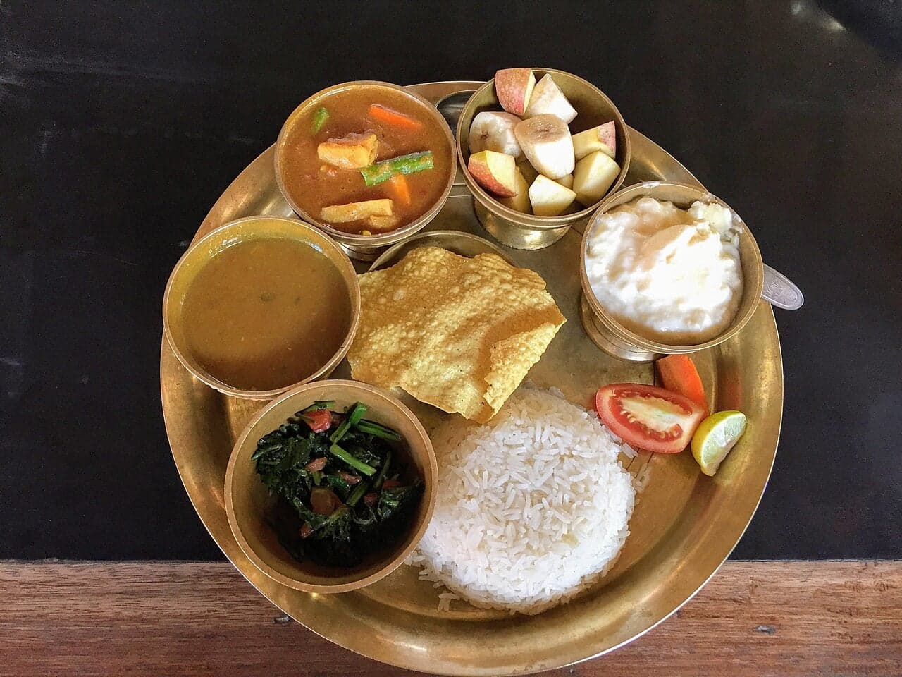 A plate of dal bhat with rice, lentil soup, curry and pickle