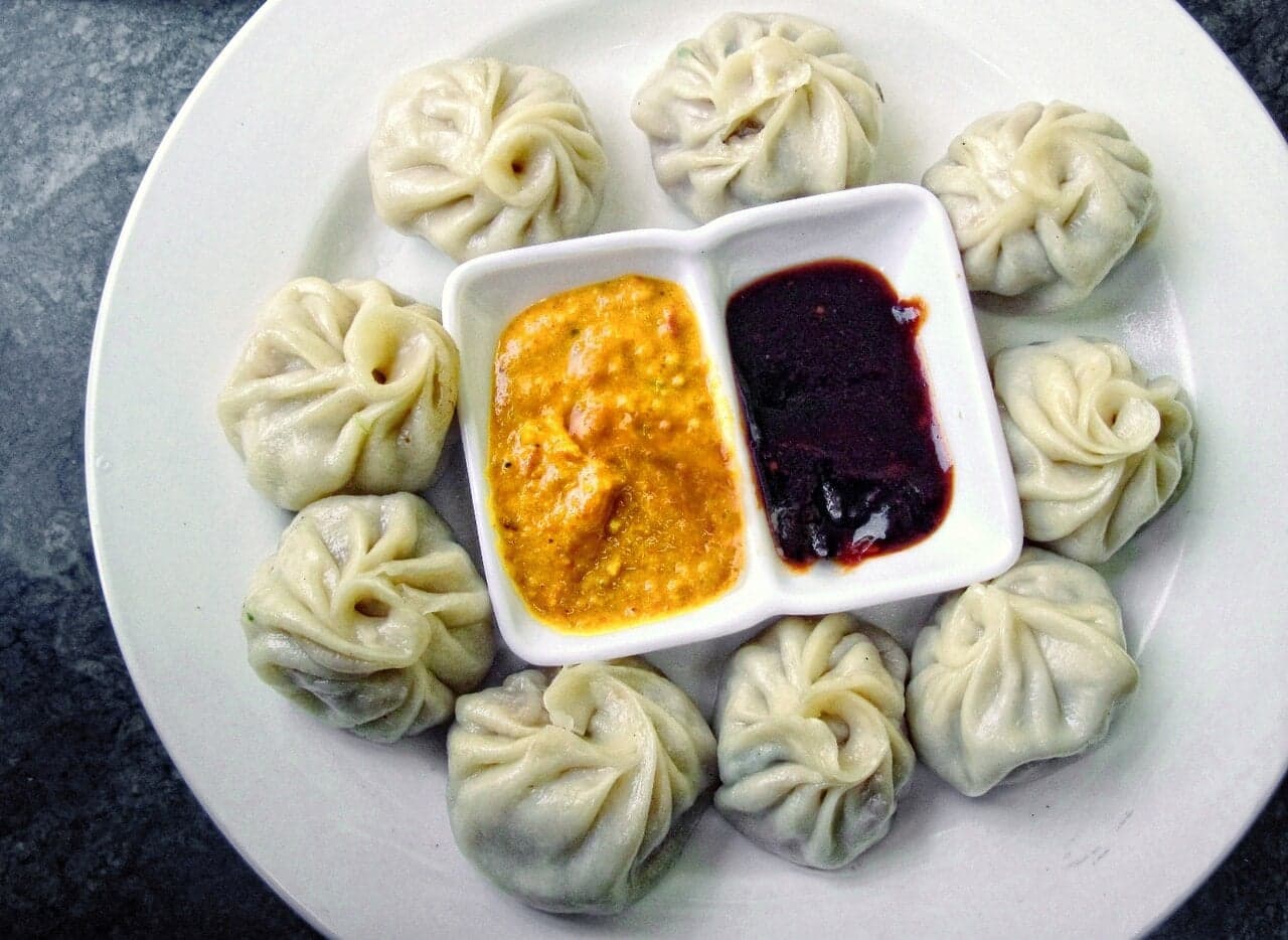 A plate of fresh steamed momos with dipping sauce