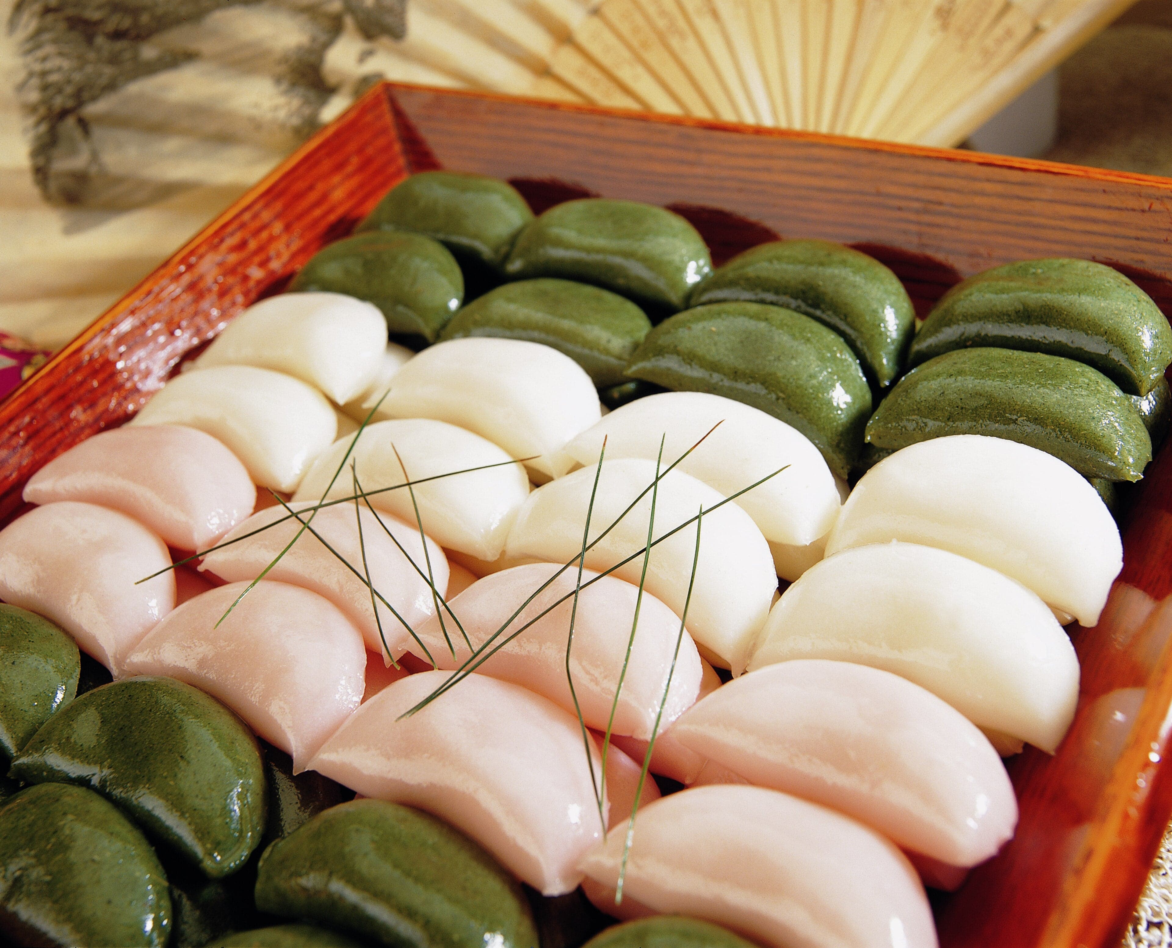 A Korean family in traditional hanbok clothes setting out fruit and rice cakes under a bright full moon