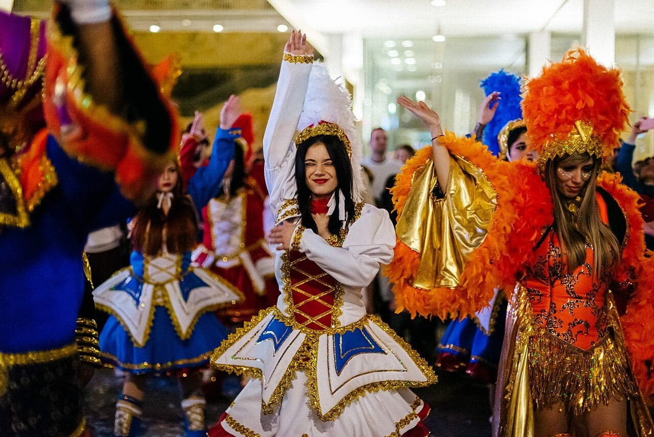Dancers in elaborate feathered costumes parading through a brightly lit carnival street in Encarnación