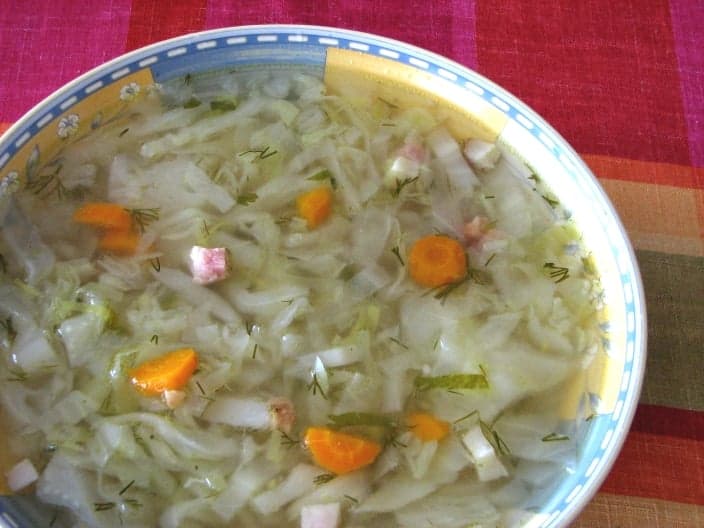 A bowl of thick cabbage soup with sausage slices and dried mushrooms