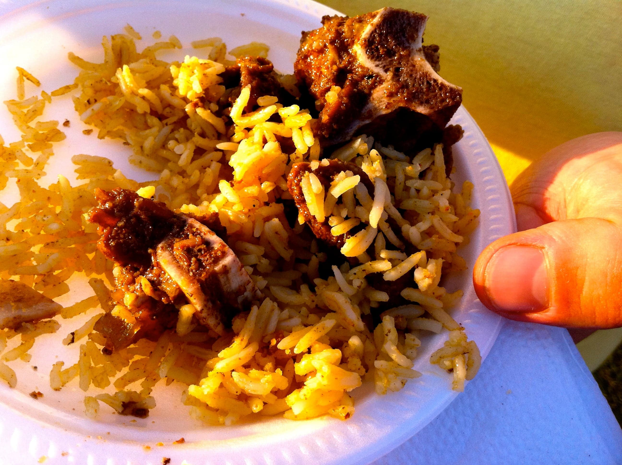 A large bowl of golden spiced rice garnished with raisins and topped with slow-cooked meat