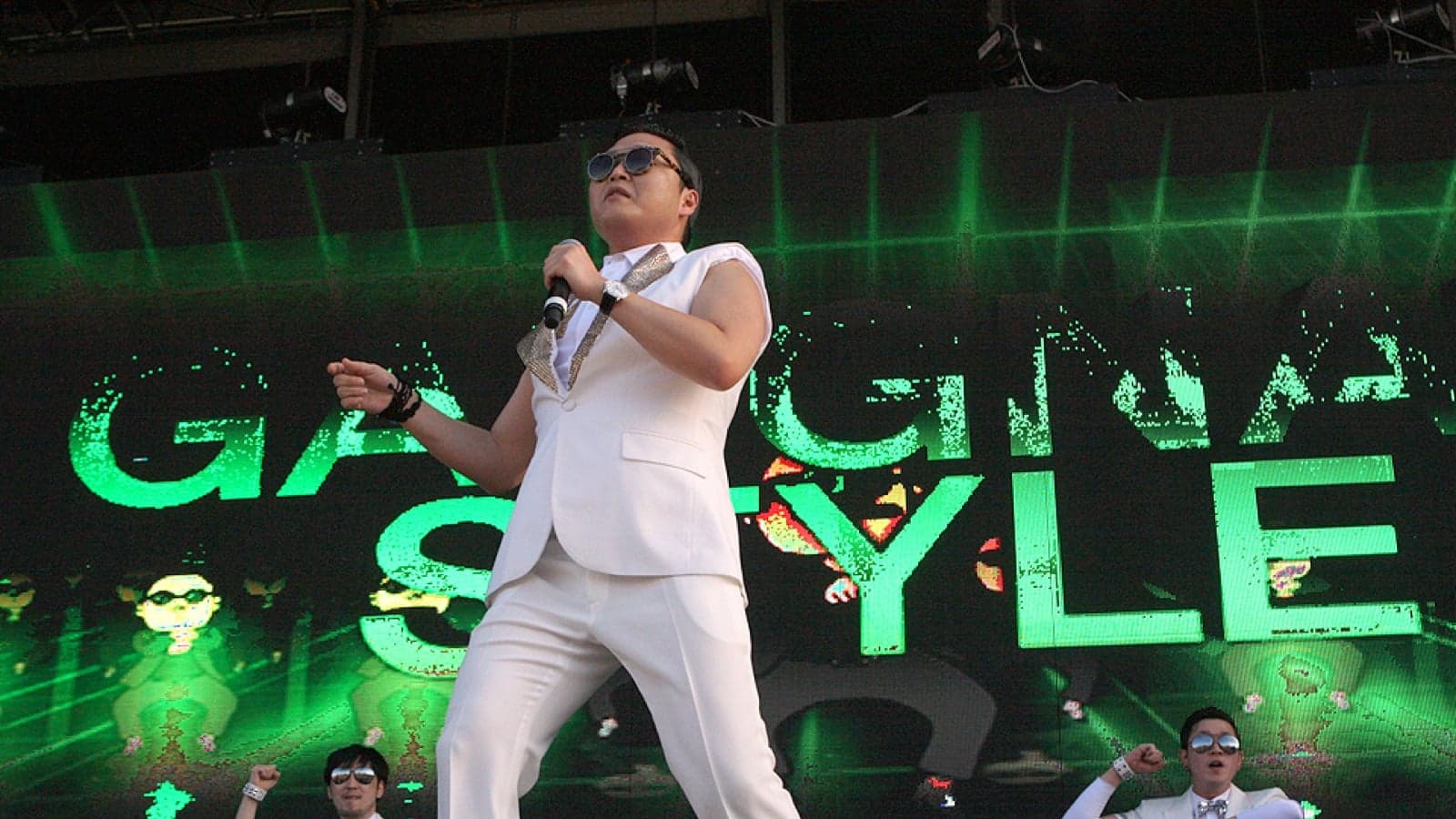 A Korean singer in a white suit performing on a brightly lit stage