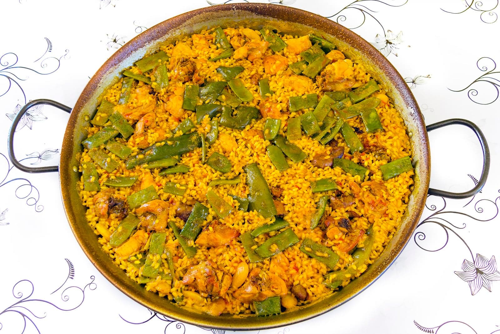 A pan of paella valenciana with rice, chicken, green beans and saffron