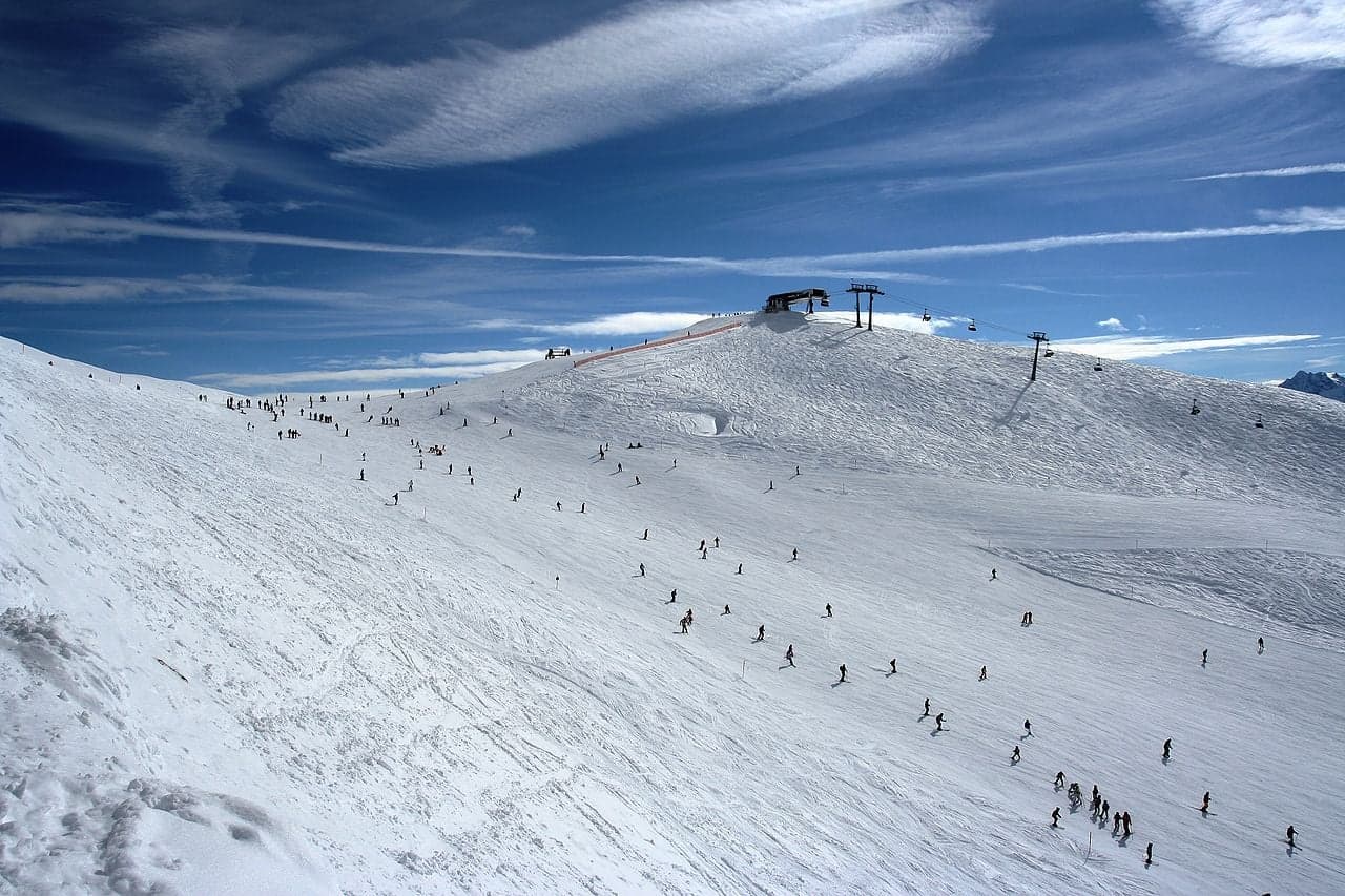 Skiers on a snowy slope in the Swiss Alps with mountains in the background