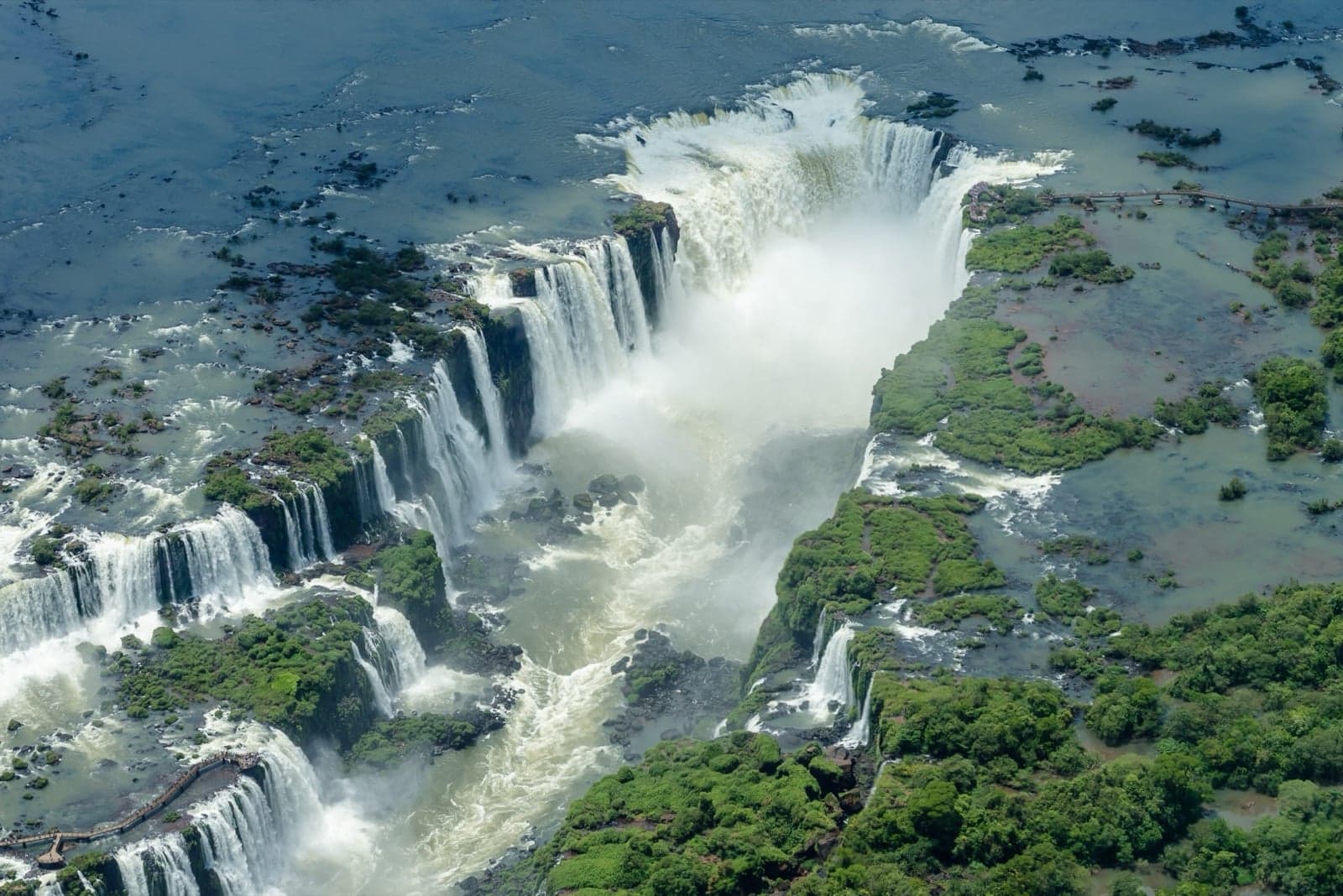 An aerial view of the Iguazú Falls with mist rising over the jungle