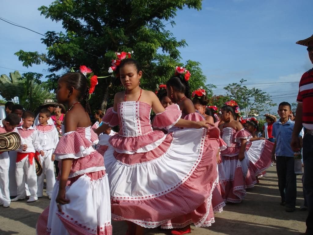 A vallenato musician playing a red accordion in a Colombian coastal town