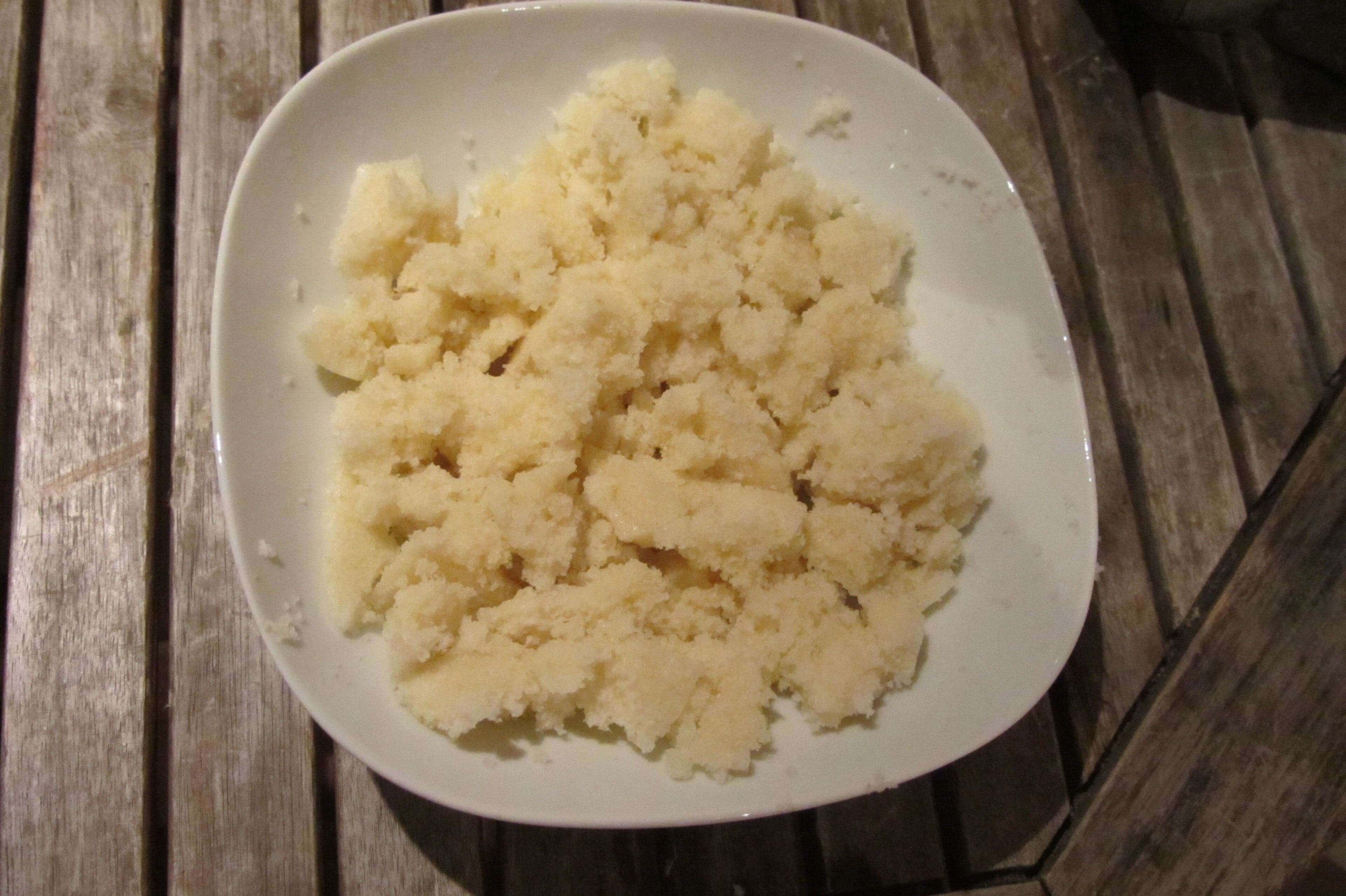 A bowl of fluffy white attiéké cassava semolina on a wooden table