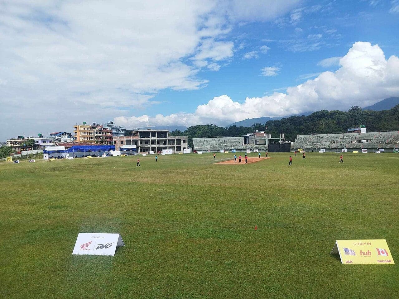 Children playing cricket on a dusty pitch with the Himalayas in the background