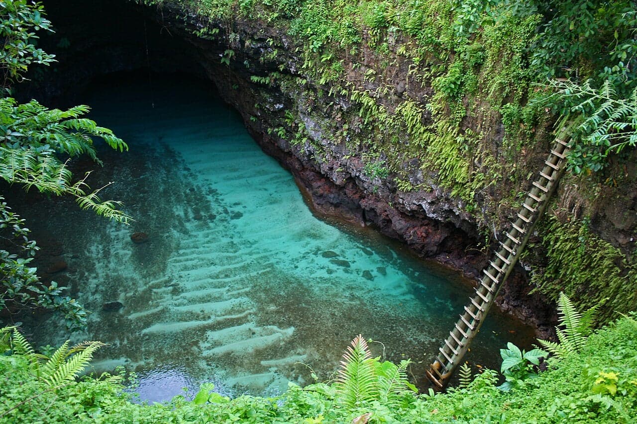 A deep round blue swimming hole surrounded by green tropical plants