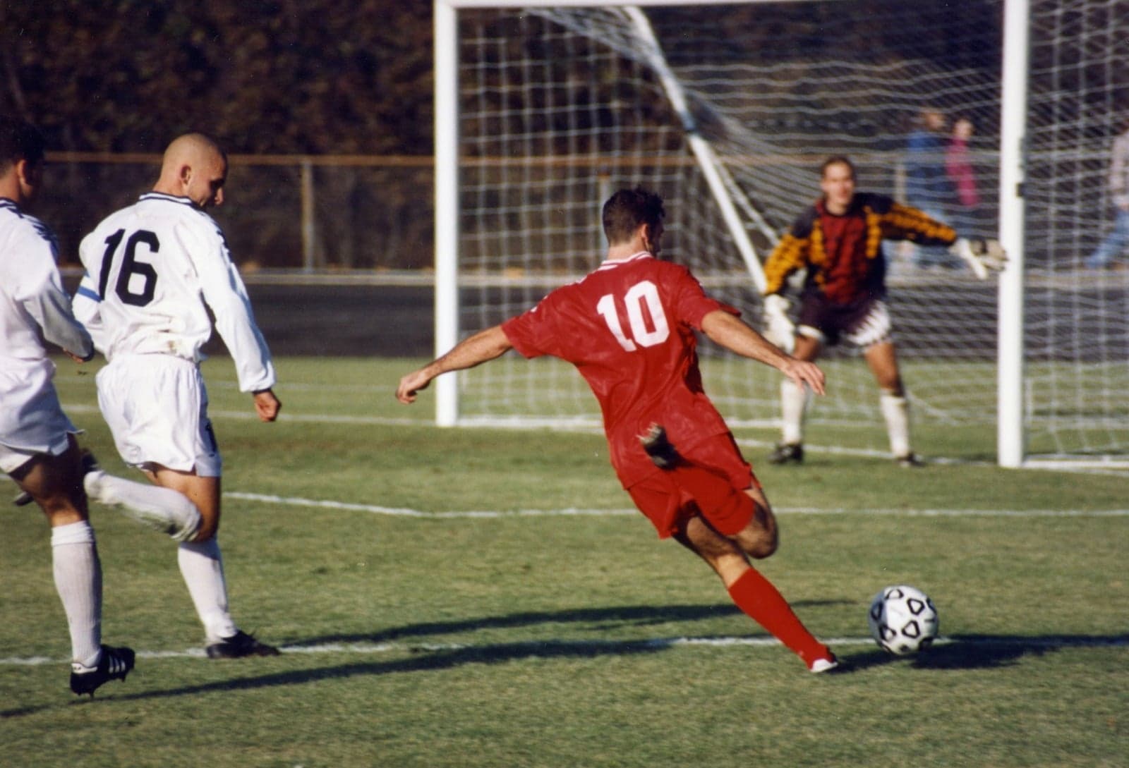 Football players in action - one in red about to strike the ball at goal